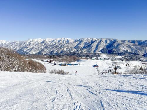 a snowy ski slope with mountains in the background at Blue Star Hotel in Chikuni