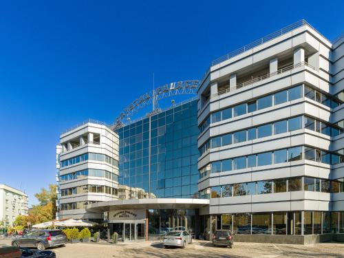 a tall glass building with cars parked in front of it at Crystal Palace Hotel in Bucharest