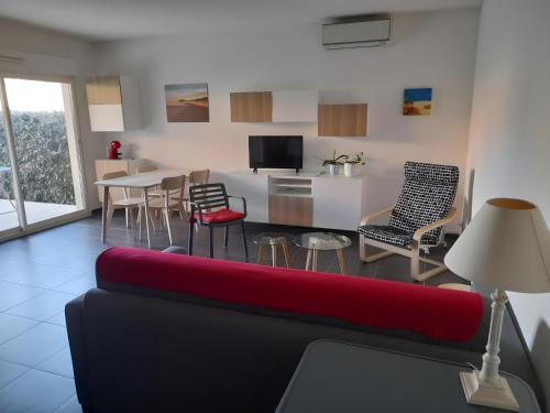 un salon avec un canapé rouge et une cuisine dans l'établissement Bleu-Estérel, 50m de la plage, appartement 4 personnes, à Saint-Raphaël