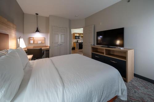 a hotel room with a bed and a flat screen tv at Candlewood Suites Baytown by IHG in Baytown