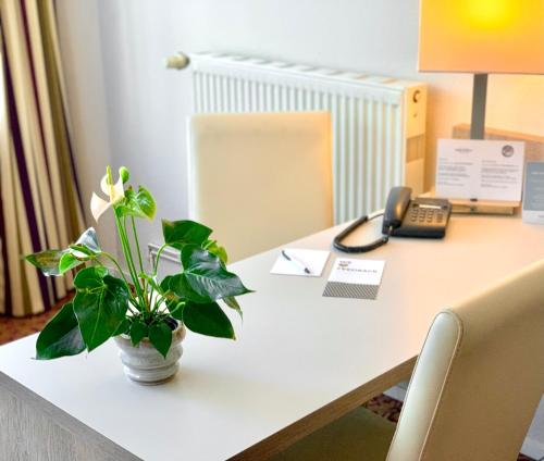 a desk with a phone and a plant on it at Mercure Hotel Hamburg am Volkspark in Hamburg