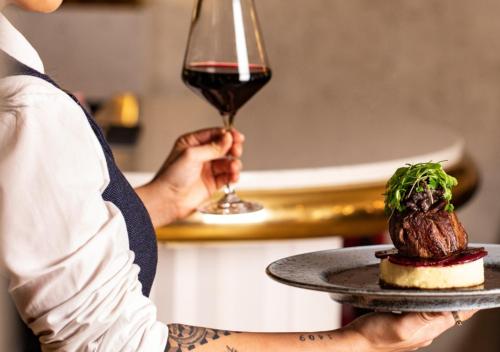 a person holding a plate with a glass of wine at The Morgan Hotel in Dublin