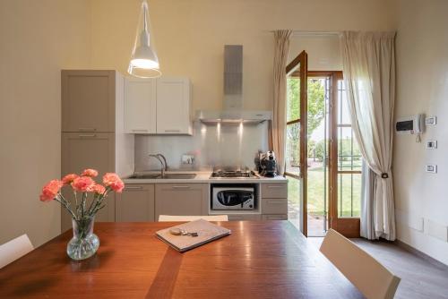 a kitchen with a table with a vase of flowers on it at Podere Vignanova Accommodations & SPA in Castagneto Carducci