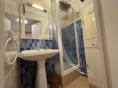 une salle de bain carrelée bleue avec un lavabo et une douche dans l'établissement STUDIO 1ERE LIGNE MER AVEC PARKING, à Sète