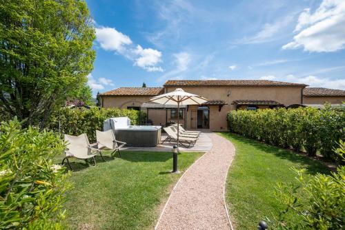 a garden with chairs and an umbrella in front of a house at Podere Vignanova Accommodations & SPA in Castagneto Carducci