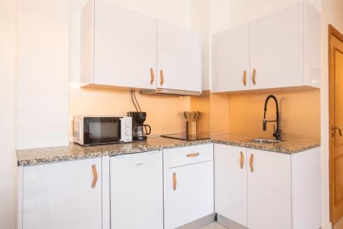 a kitchen with white cabinets and a microwave at Studio Oporto (Gaia) in Vila Nova de Gaia