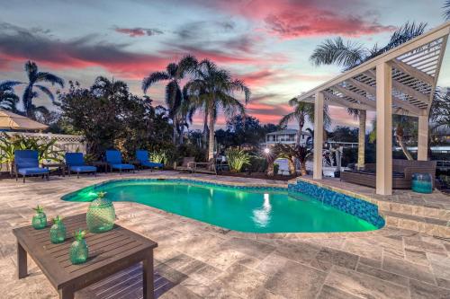 a pool with a table and chairs and a sunset at Isla Amor - 86 in Siesta Key