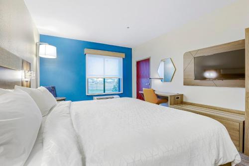 a bedroom with a white bed and a blue wall at Holiday Inn Express - Gulfport Beach by IHG in Gulfport