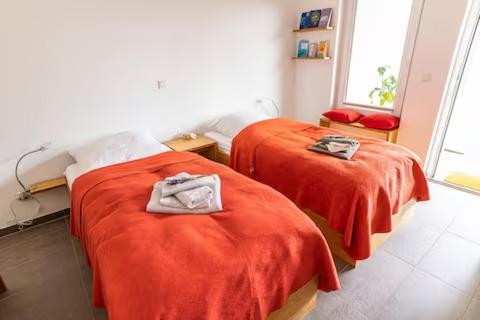 two beds in a room with orange sheets and towels at Haus AchtsamZeit in Hentern