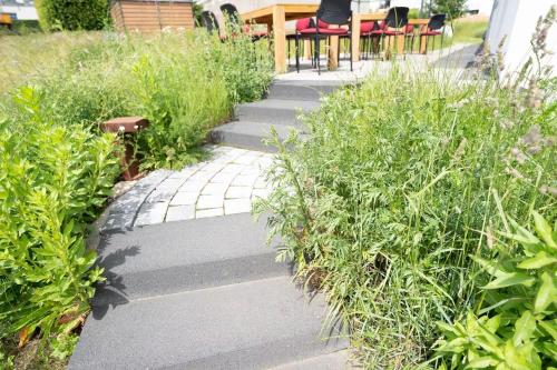 a garden with a walkway with chairs and plants at Haus AchtsamZeit in Hentern