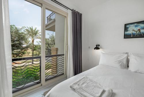 a bedroom with a bed and a large window at Sunny Cairo City Center l Serviced l Golf l Pool l Gym l 1 in Cairo