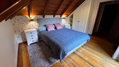 a bedroom with a bed with blue sheets and pink pillows at Casa dos Lamaceiros in São Vicente