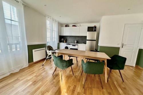 une cuisine avec une table en bois et des chaises vertes dans l'établissement Charming T3 on the seafront, à Villers-sur-Mer