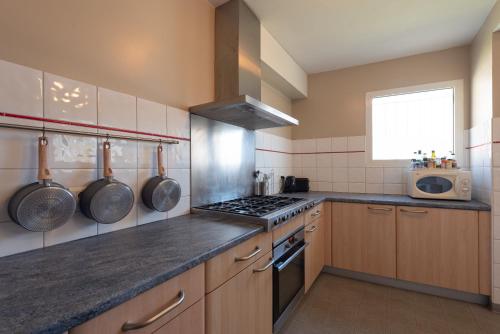 une cuisine avec des armoires en bois et un four à plaques de cuisson dans l'établissement Gîte Le Bérierot avec piscine, à Ouzous