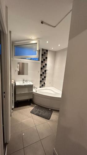 une salle de bain avec une baignoire et un lavabo et une baignoire dans l'établissement Appartement Épuré Proche Centre-Ville de Besançon, à Besançon