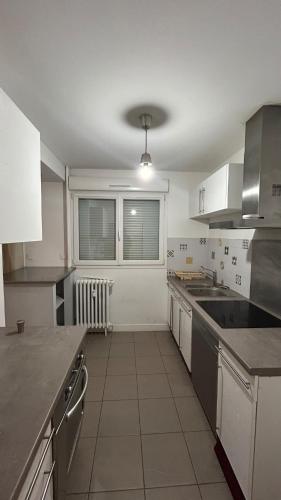 une grande cuisine avec des placards blancs et un comptoir dans l'établissement Appartement Épuré Proche Centre-Ville de Besançon, à Besançon