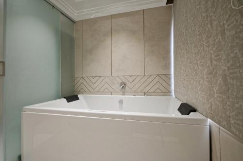 a white tub in a bathroom with a wall at Golden Plaza in Ahmedabad