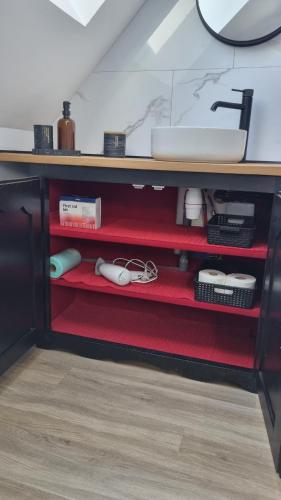 - un comptoir de cuisine avec des étagères rouges et un évier dans l'établissement Le Grenier, à Goussainville