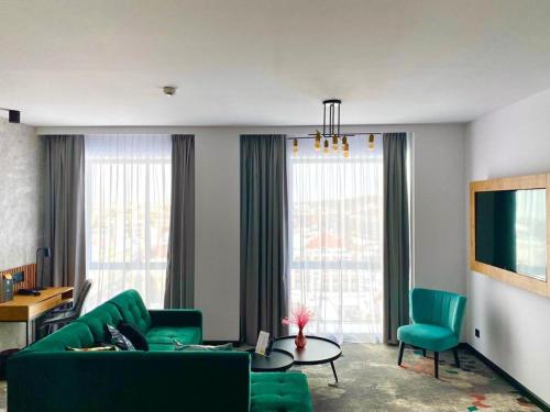 a living room with a green couch and chairs at Focus Hotel Premium Bydgoszcz in Bydgoszcz