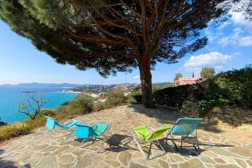 Deux chaises et un arbre à côté de l'océan dans l'établissement Family villa with sea view classified 3 - 8 people, au Lavandou