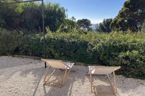 deux chaises assises dans le sable devant un bush dans l'établissement Sea View Studio with Large Terrace 5-Min Walk to the Beach, au Lavandou