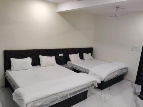 RāipurHotel Anand shree的一间白墙房间里有两张床