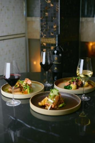 a table with three plates of food and wine glasses at Hotel Keflavik by Reykjavik Keflavik Airport in Keflavík
