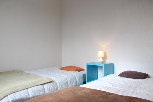 Cette chambre comprend deux lits et une table bleue avec une lampe. dans l'établissement Appt 3 pièces - CHATELAILLON PLAGE - CL130-212, à Châtelaillon-Plage