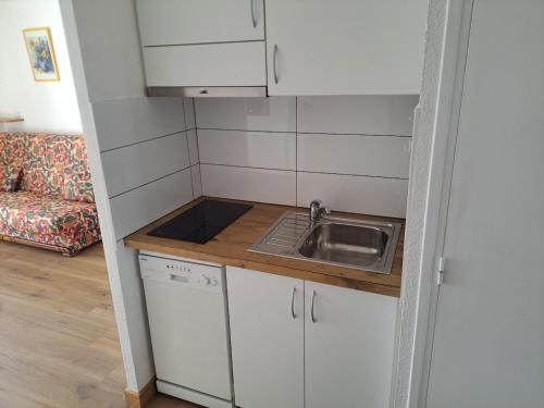 une petite cuisine avec des armoires blanches et un évier dans l'établissement Port Brescou III, T2 au centre port avec parking et clim, au Cap d'Agde