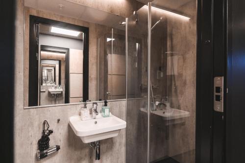 a bathroom with a sink and a glass shower at Svalbard Hotell | The Vault in Longyearbyen