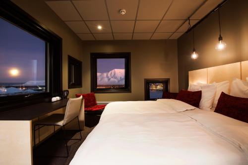 a bedroom with a bed and a desk and a window at Svalbard Hotell | The Vault in Longyearbyen