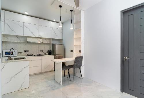 a kitchen with white cabinets and a table and chairs at Ukulhas Sands in Ukulhas