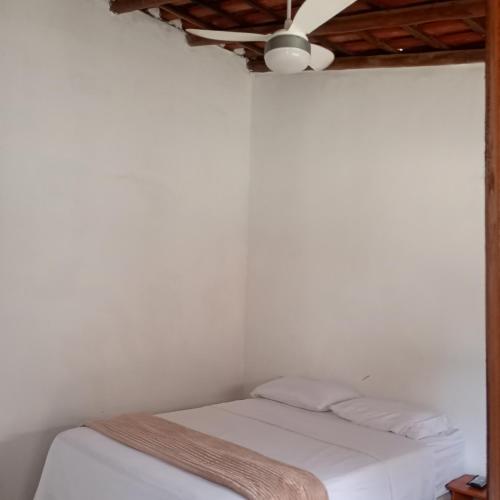 a bedroom with a white bed with a ceiling fan at Suítes na Beira do mar in Canavieiras