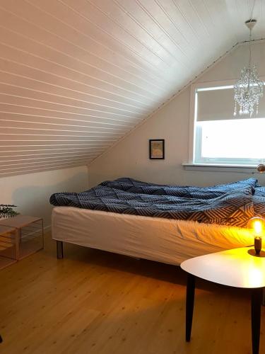 a bed in a room with a window and a table at The Northern Escape in Klaksvík