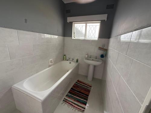 a white bathroom with a tub and a sink at Vumasky in Ladysmith