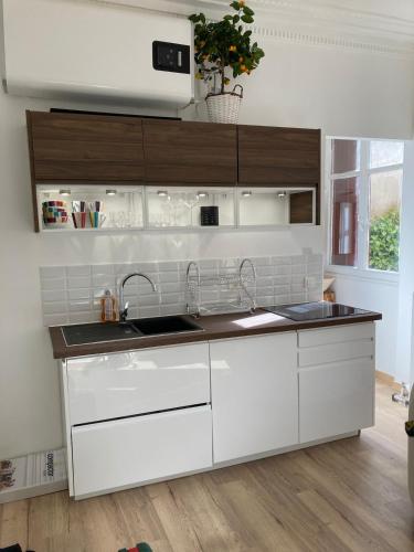 une cuisine avec des armoires blanches et un évier dans l'établissement Little Home Versailles, à Versailles