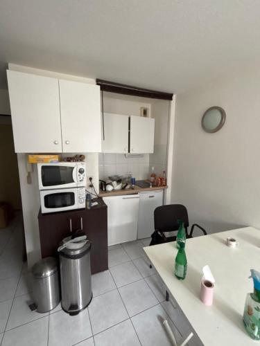une petite cuisine avec des armoires blanches et une table dans l'établissement Appartement cosy 2 pièce, à Perpignan