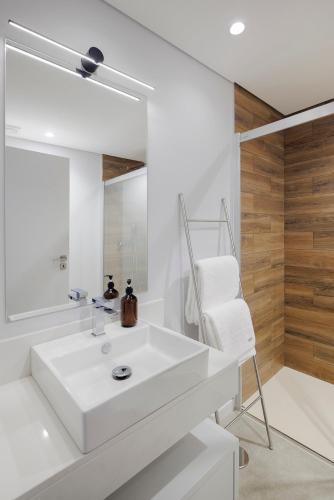a white bathroom with a sink and a mirror at Casa de Viriato in Funchal