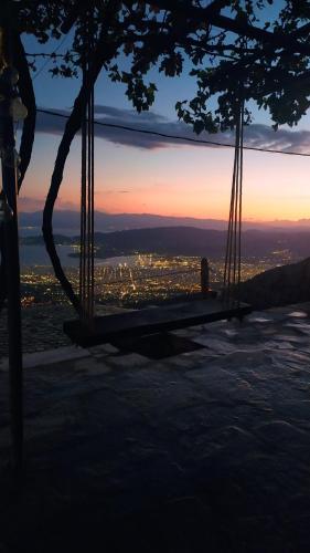 a swing with a view of a city at dusk at Μακρινίτσα Αλώνια in Makrinítsa