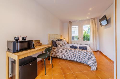 a bedroom with a bed and a desk with a microwave at Villa Pattos in Santa Coloma de Farners