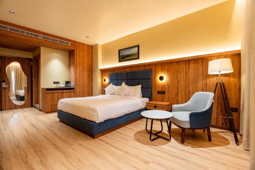 a hotel room with a bed and a chair at The White Rock Inn & Dine in Shillong