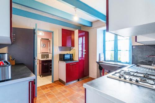 une cuisine avec des placards rouges et une porte rouge dans l'établissement La Villa Tara, à Sarzeau