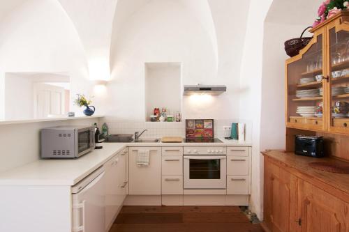 a kitchen with white cabinets and a microwave at Hotel Landsitz Pichlschloss in Neumarkt in Steiermark