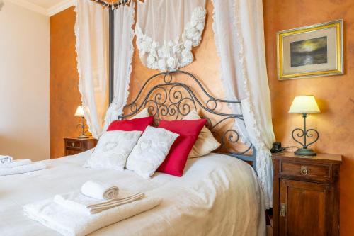a bedroom with a white bed with red pillows at Villa il Mandorlo by VacaVilla in Passignano sul Trasimeno