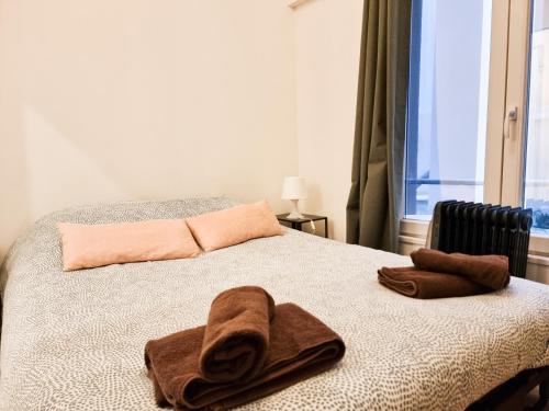 a bed with two towels on it with a window at EXIGEHOME-Versailles à 2 pas du château in Versailles