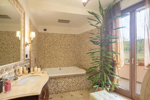 a bathroom with a tub and a sink and a large plant at Villa il Mandorlo by VacaVilla in Passignano sul Trasimeno