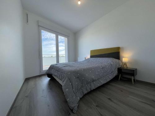 une chambre avec un lit et une grande fenêtre dans l'établissement Appt 3 pièces LA ROCHELLE - LR670-303, à La Rochelle