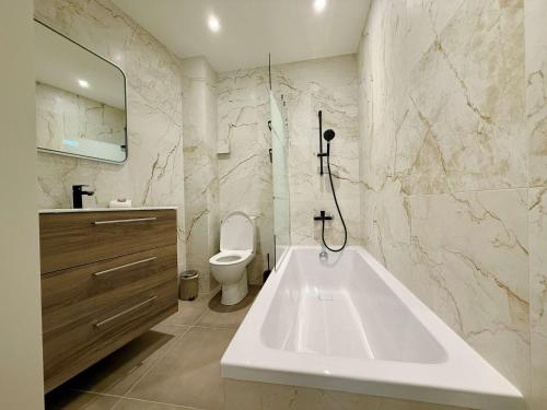 une salle de bain avec une baignoire blanche et des toilettes dans l'établissement C083 Croisette - 1 chambre - Vue Epoustouflante, à Cannes