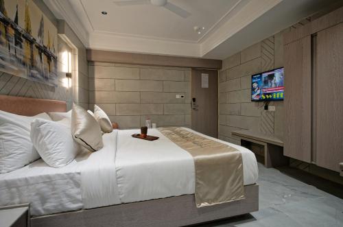 a bedroom with a large white bed with a television at Golden Plaza in Ahmedabad