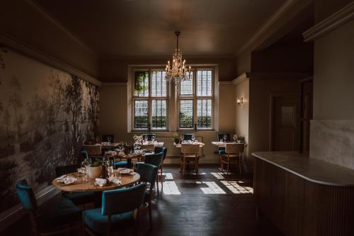 a dining room with tables and chairs and a chandelier at Weston Hall Hotel Sure Hotel Collection by Best Western in Bulkington